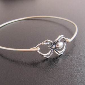 Pode incluir: Um bracelete de prata com um fecho de aranha. A aranha &eacute; detalhada e tem uma apar&ecirc;ncia realista.