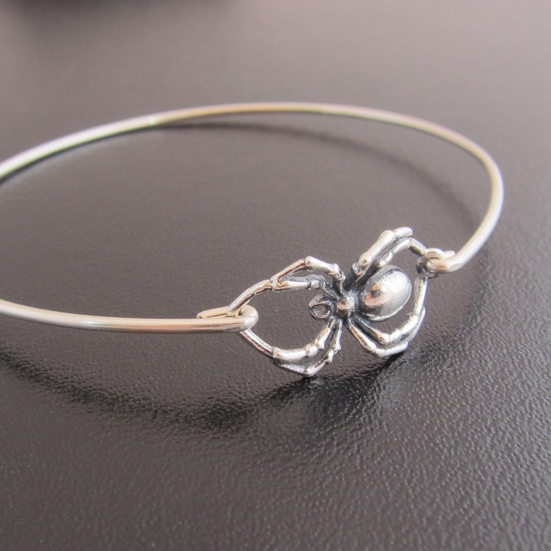 Pode incluir: Um bracelete de prata com um fecho de aranha. A aranha &eacute; detalhada e tem uma apar&ecirc;ncia realista.