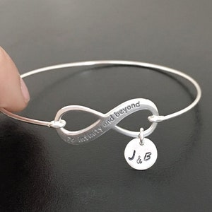 May include: Silver infinity bracelet with the inscription "To infinity and beyond" and a charm with the initials "J & B".