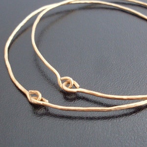 May include: Two gold-toned bangle bracelets with hammered textures and simple, looped closures.