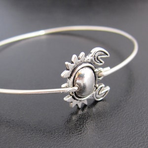 May include: A silver bangle bracelet with a crab charm. The charm is detailed with a textured shell and claws.