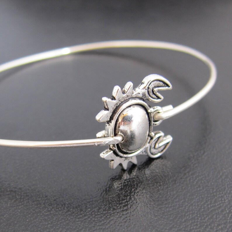May include: A silver bangle bracelet with a crab charm. The charm is detailed with a textured shell and claws.