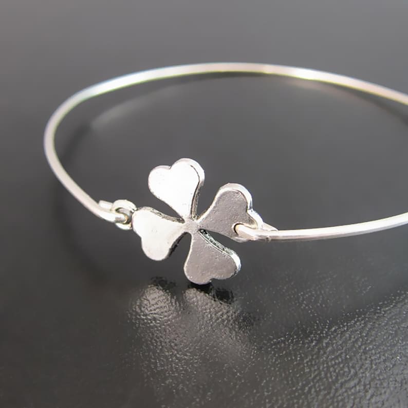 May include: A silver bracelet with a four-leaf clover charm.