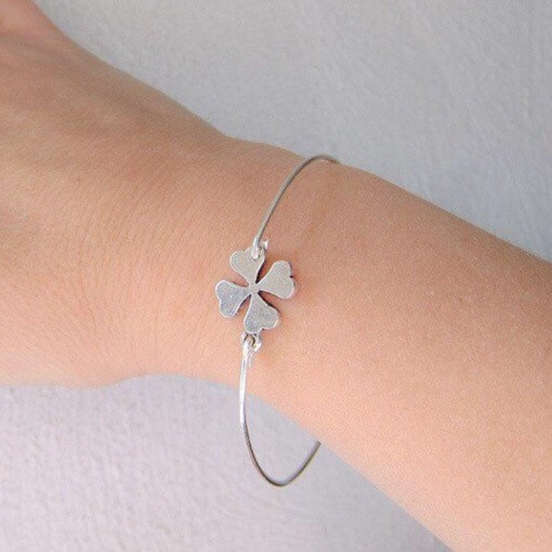 May include: A silver bracelet with a four-leaf clover charm.