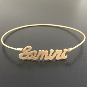 May include: A gold-toned bangle bracelet with the name "Samira" written in a cursive font.