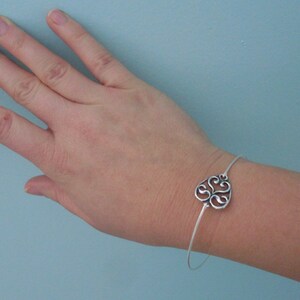 Puede incluir: Una pulsera de plata con un delicado encanto adornado en forma de coraz&oacute;n. El encanto presenta un dise&ntilde;o en espiral e intrincado.