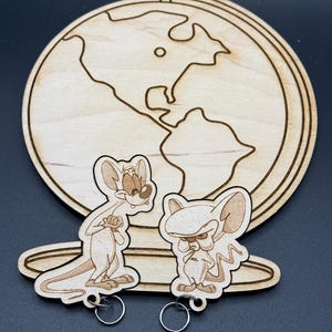 May include: A wooden globe with a brown outline of the continents. Two wooden keychains with cartoon images of a mouse are attached to the globe. The keychains have silver rings.
