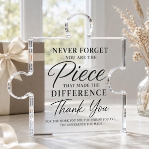May include: A clear acrylic puzzle piece plaque featuring black printed text that reads: NEVER FORGET YOU ARE THE Piece THAT MADE THE DIFFERENCE Thank You FOR THE WORK YOU DID, THE PERSON YOU ARE, THE DIFFERENCE YOU MADE in a mix of fonts.