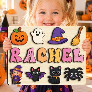 Pode incluir: Um quebra-cabeça de madeira com o nome RACHEL em letras grandes e coloridas. O tabuleiro inclui peças com tema de Halloween: uma abóbora, um fantasma, um chapéu de bruxa roxo, uma vassoura, uma bruxa, um morcego, um gato preto e uma aranha.