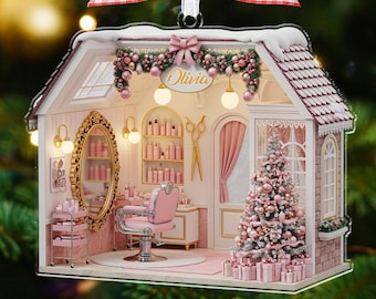 May include: A festive Christmas tree ornament in the shape of a salon, predominantly pink and white. It features a barber chair, a Christmas tree, and the name "Olivia". The ornament is topped with a red and white gingham bow.