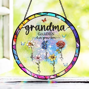 Peut inclure: Un attrape-soleil rond en verre teinté avec une bordure arc-en-ciel. Le centre présente un motif floral avec le texte "grandma garden love grows here".
