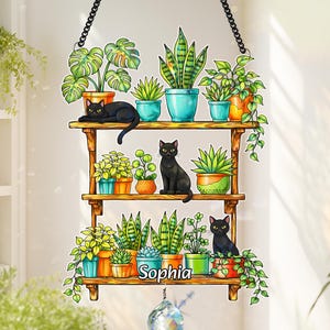 May include: A decorative wooden shelf with three tiers, adorned with potted plants and black cats. The plants are in various colorful pots. The name "Sophia" is displayed on the bottom shelf. A crystal prism hangs below.