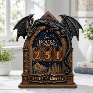 May include: A brown, arched book tracker featuring a black dragon perched on top. The center displays the text 'BOOKS READ THIS YEAR' above three rotating number tiles showing '251', with a mountain and castle scene below and 'RACHEL'S LIBRARY' at the base.