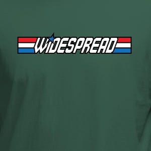 May include: A dark green t-shirt featuring the word "WIDESPREAD" in white, framed by a red, white, and blue rectangular design. The shirt's solid colour contrasts with the bold text and graphic.