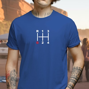 May include: Royal blue t-shirt featuring a white and red gear shift pattern. The graphic includes the letters "R", "1", "3", "2", and "4", with "G" in red. The shirt is a casual wear item.