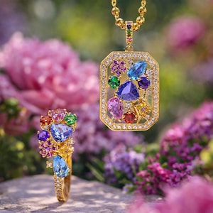 May include: A gold pendant necklace and ring set with colorful gemstones. The rectangular pendant features a variety of gems, including blue, purple, green, and pink stones, surrounded by a border of small diamonds. The ring has a similar design, with a cluster of colorful gemstones.