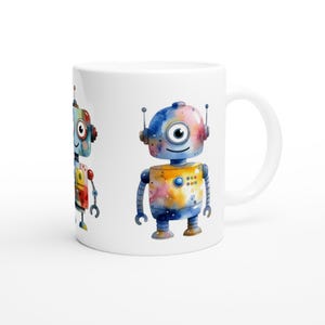 Könnte beinhalten: Weiße Keramiktasse mit zwei farbenfrohen Roboterillustrationen. Die Roboter haben Antennen, runde Augen und sind mit Aquarell-Spritzern in Blau, Gelb, Rot und Orange bemalt. Die Tasse hat einen gebogenen Griff.