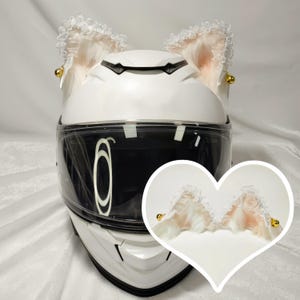 May include: White motorcycle helmet with a pair of white lace cat ears with gold accents attached to the top.
