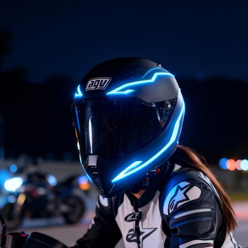 May include: Black motorcycle helmet with blue LED accents. The helmet has a dark visor and the brand logo "agu" is visible. The helmet is worn by a person wearing a black and white leather jacket.