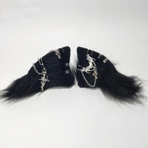 May include: A pair of black faux fur hair clips with silver chains, crosses, and a bat charm.