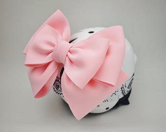May include: A pink bow tied on a white helmet with a black and white bandana. The bow is large and fluffy.