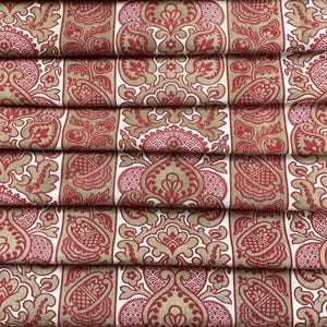 May include: Close-up of folded fabric featuring a repeating pattern of red and tan floral and geometric designs. The fabric is arranged in vertical stripes with alternating patterns. The overall aesthetic is ornate and traditional.