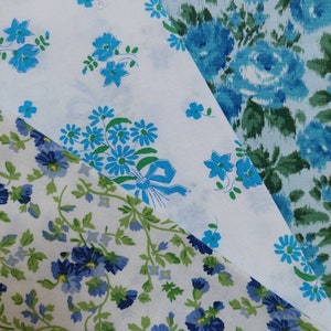 Pode incluir: Três amostras de tecido branco diferentes com padrões florais azuis. A amostra superior tem um padrão floral azul maior com um laço azul. A amostra do meio tem um padrão floral azul menor. A amostra inferior tem um padrão floral azul menor com folhas verdes.