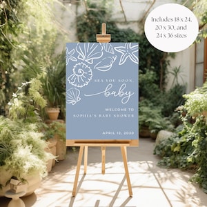 May include: A light blue baby shower sign on a wooden easel. The sign features white seashell illustrations and the text "Sea You Soon, Baby. Welcome to Sophia's Baby Shower, April 12, 2030." Includes 18 x 24, 20 x 30, and 24 x 36 sizes.