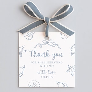 Könnte beinhalten: Ein quadratisches Geschenk-Etikett mit einer blau-weißen Schleife. Das Etikett hat einen hellen Hintergrund mit blauen Muschel-Illustrationen und den Worten "thank you" in Schreibschrift. Der Text "FOR SHELLEBRATING WITH ME! with love, OLIVIA" steht ebenfalls auf dem Etikett.