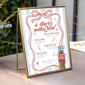 May include: A framed sign with a gold metal frame. The sign has a light blue and white striped background and features the words "dirty soda bar" in red script. The sign lists soda flavors and ingredients, with a Coca-Cola bottle illustration.