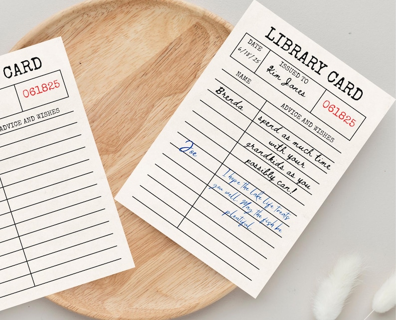 May include: Two vintage-style library cards on a wooden tray. The cards have a cream background with black lines and text, including the words "LIBRARY CARD" and "ADVICE AND WISHES." One card has handwritten notes in blue ink.