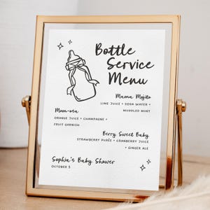 May include: A gold framed sign with a white background. The sign reads "Bottle Service Menu" with drink recipes. The menu includes "Mama Mojito", "Mom-osa", and "Berry Sweet Baby". The sign is for "Sophia's Baby Shower".
