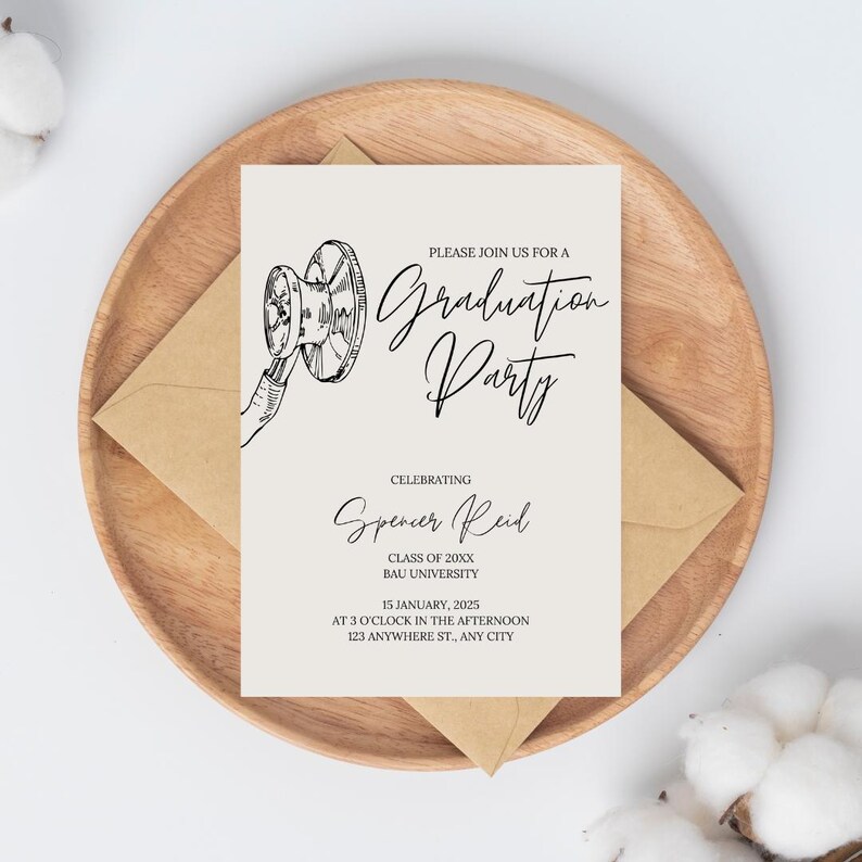 A minimalist nurse graduation party invitation with a hand drawn stethoscope and script text, sitting atop an envelop and a wood bowl