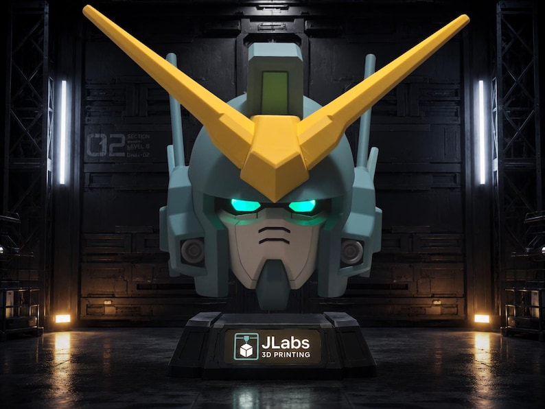 May include: A blue and yellow robotic head bust featuring a V-shaped crest, glowing cyan eyes, and a dark gray base with a label that reads JLabs 3D PRINTING. The design includes geometric panels and antenna-like structures on the sides of the head.