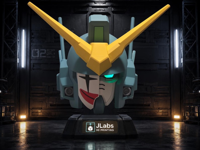 May include: A stylized robot head bust featuring a blue helmet with a large yellow V-shaped crest. The face is split, with one side showing a white clown mask with a red smile and black eye markings, while the other side has a glowing cyan eye. The base displays the text JLabs 3D PRINTING.