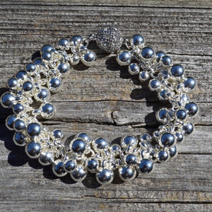 May include: A silver bracelet with a cluster of round beads and a sparkly silver charm.