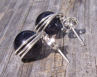 May include: A pair of silver earrings with dark blue gemstone beads wrapped in silver wire.