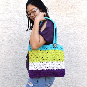 May include: A multi-colored crocheted tote bag with a wooden button. The bag is made with turquoise, lime green, white, and purple yarn.