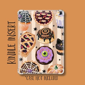 May include: A rectangular Kindle insert featuring a pattern of Halloween-themed baked goods including cupcakes, pies, and cookies on a beige striped background. The text KINDLE INSERT and *CASE NOT INCLUDED is printed on the sides.