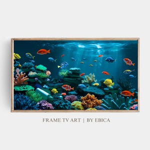 May include: A framed underwater scene with colorful fish swimming among coral reefs. The fish are orange, yellow, blue, and red. The coral reefs are pink, green, and brown. The background is a deep blue.