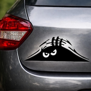 Puede incluir: Una taza de cerámica blanca con asa negra y el texto "But First, Coffee" en negrita negra. La taza se encuentra sobre un fondo borroso, sugiriendo un ambiente acogedor.