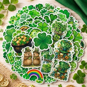 Op de afbeelding: Een verzameling gestanste stickers met diverse groene klavers, klavertjesvier, kabouterhoeden, potten met goudstukken, regenbogen en twee bruine bosmarmotten met groene hoedjes, gerangschikt in een cirkelvormig patroon op een houten ondergrond.
