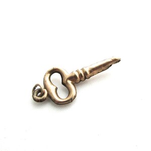 Puede incluir: Un dije de llave dorado con un lazo en forma de coraz&oacute;n y un bucle para sujetarlo a un collar o pulsera.