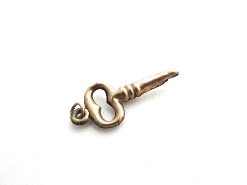 Puede incluir: Un dije de llave dorado con un lazo en forma de coraz&oacute;n y un bucle para sujetarlo a un collar o pulsera.