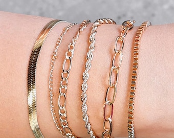 Conjunto de pulseras apilables de oro, delicadas cadenas superpuestas, joyería minimalista de lujo ajustable.