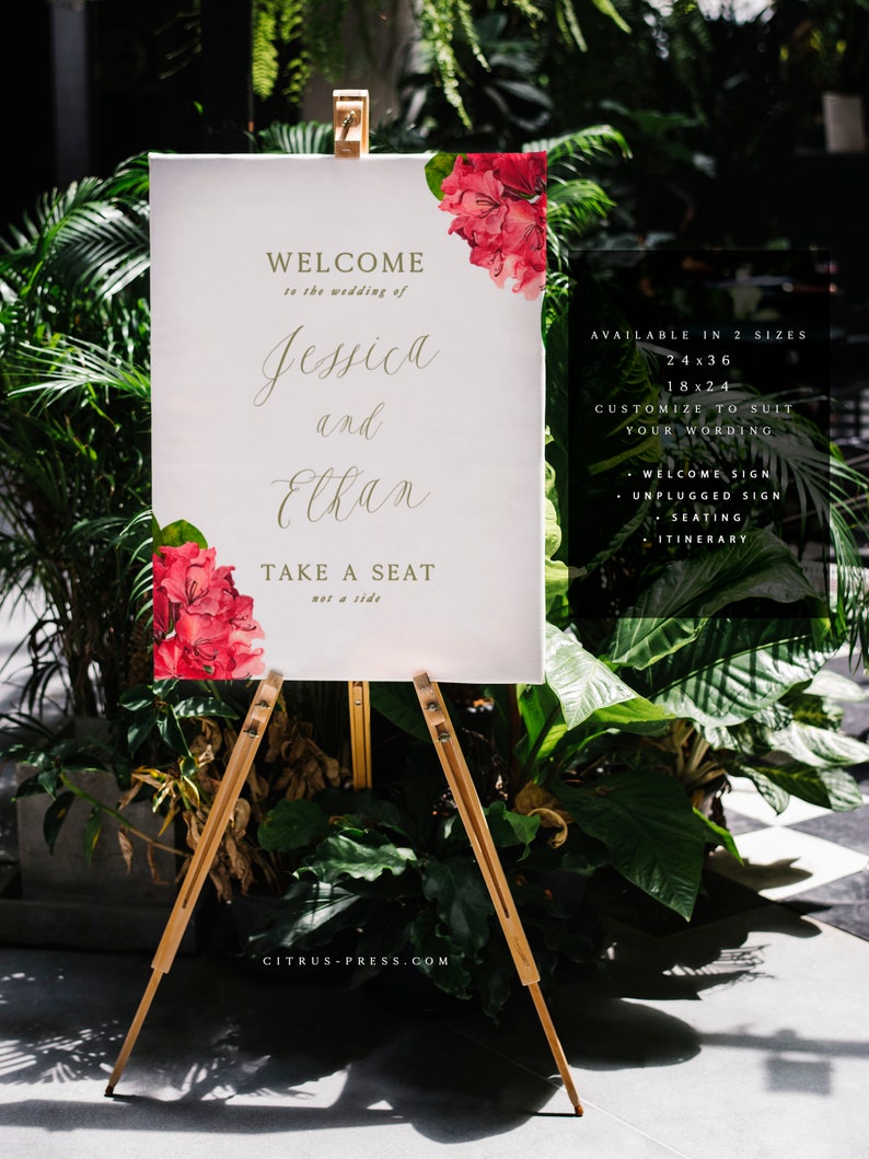 May include: A white welcome sign with gold lettering for a wedding. The sign says "Welcome to the wedding of Jessica and Elkan. Take a seat, not a side." The sign is decorated with red flowers and is on a wooden easel. The sign is available in two sizes: 24x36 inches and 18x24 inches. The sign can be customized to suit your wording. It can be used for a welcome sign, unplugged sign, seating chart, or itinerary.