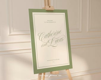 May include: A wedding welcome sign on an easel. The sign has a sage green border and features elegant script that reads "Welcome to the Wedding of Catherine and Lucas." The sign is on a wooden easel.