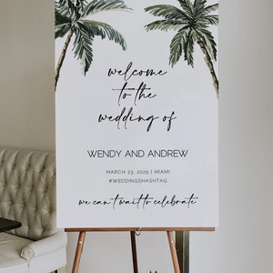 May include: A white welcome sign with a tropical theme featuring two palm trees with green leaves. The sign reads "welcome to the wedding of Wendy and Andrew, March 23, 2025 | Miami #WEDDINGSHASHTAG we can't wait to celebrate".