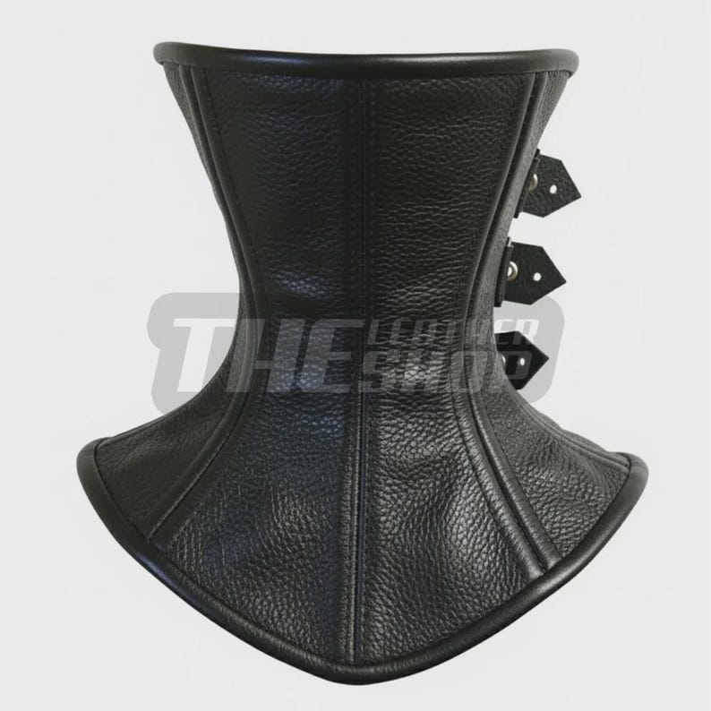 May include: Black leather corset with a high neckline and three buckle closures. The corset has a textured surface and is designed to cinch the waist. The text "THE LEATHER SHOP" is visible on the front.