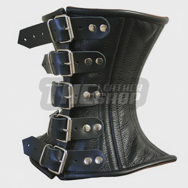 May include: Black leather corset with four rows of buckles and straps. The corset has a textured surface and a curved shape, with a wider top and bottom. Silver-colored rivets secure the straps.